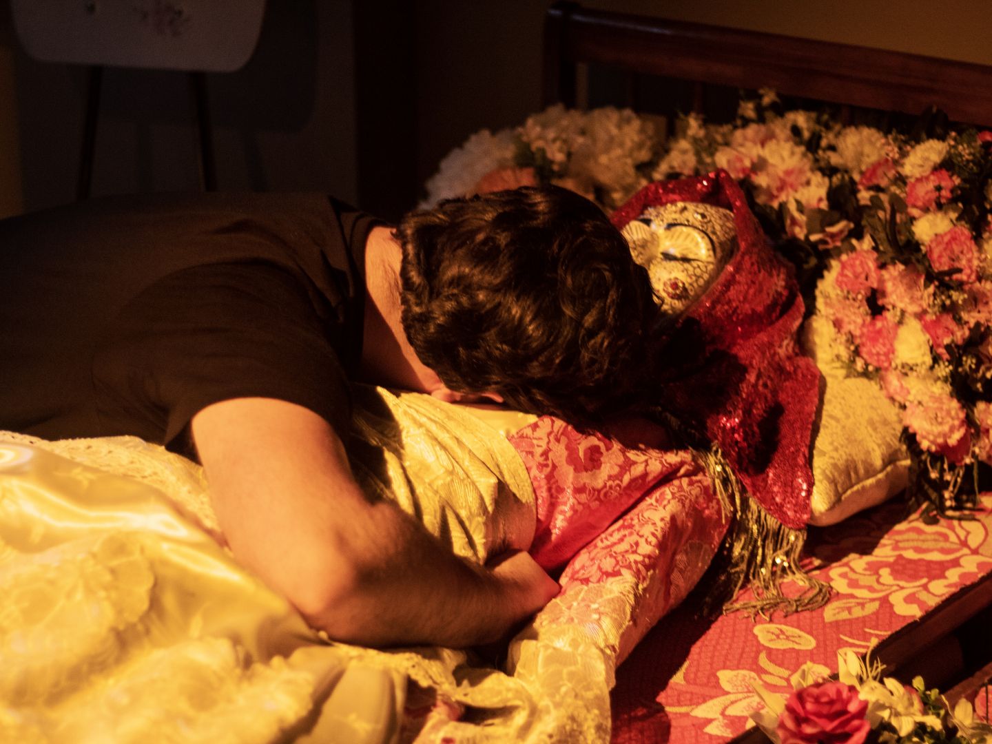 Ein Schauspieler umarmt eine Verstorbene auf ihrem Totenbett.